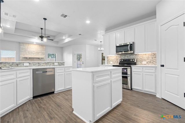 kitchen with stainless steel appliances, hanging light fixtures, and white cabinets