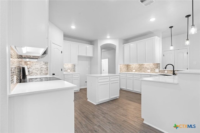 kitchen with range, decorative light fixtures, kitchen peninsula, a kitchen island, and white cabinets