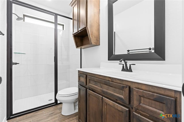 bathroom featuring hardwood / wood-style flooring, vanity, toilet, and a shower with shower door