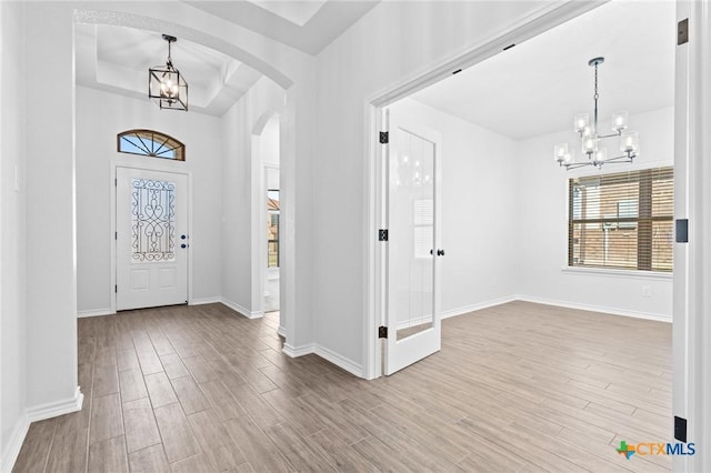 foyer featuring a notable chandelier, hardwood / wood-style floors, and a raised ceiling