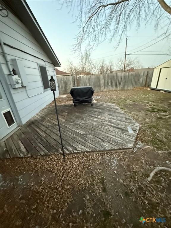 wooden deck featuring a storage shed, a fenced backyard, and an outdoor structure