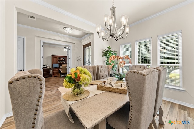 dining space featuring light hardwood / wood-style flooring, ceiling fan with notable chandelier, crown molding, and plenty of natural light