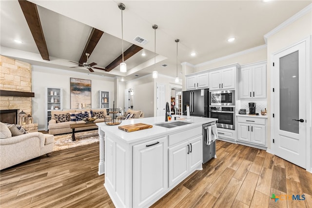 kitchen with white cabinets, sink, a kitchen island with sink, beamed ceiling, and appliances with stainless steel finishes