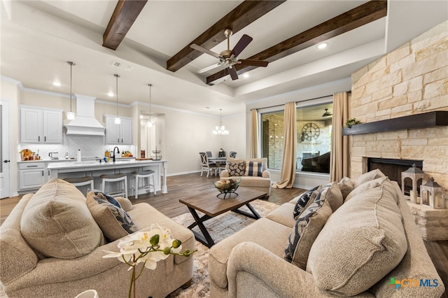 living room with a fireplace, beamed ceiling, ceiling fan with notable chandelier, and dark hardwood / wood-style flooring