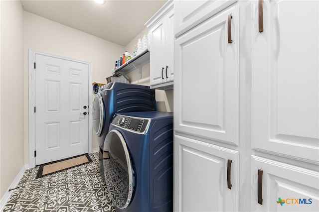 clothes washing area featuring washing machine and clothes dryer and cabinets