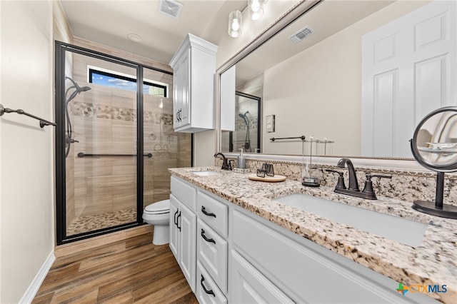 bathroom with toilet, vanity, wood-type flooring, and a shower with shower door