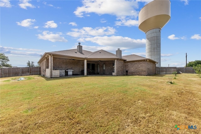 back of house featuring a lawn and a patio area