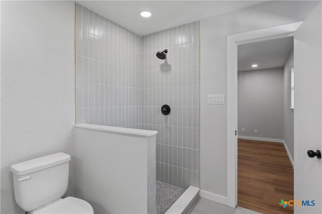 bathroom featuring toilet, wood-type flooring, and tiled shower