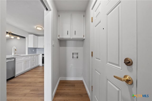 clothes washing area with cabinets, light wood-type flooring, sink, and hookup for a washing machine