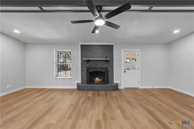 unfurnished living room with ceiling fan, light hardwood / wood-style flooring, and a brick fireplace