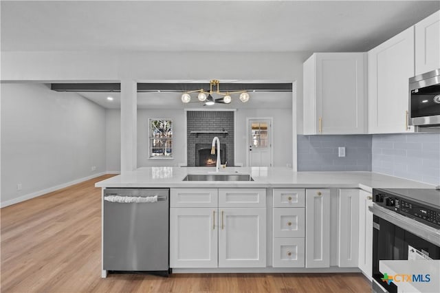 kitchen featuring decorative backsplash, appliances with stainless steel finishes, light wood-type flooring, sink, and white cabinets