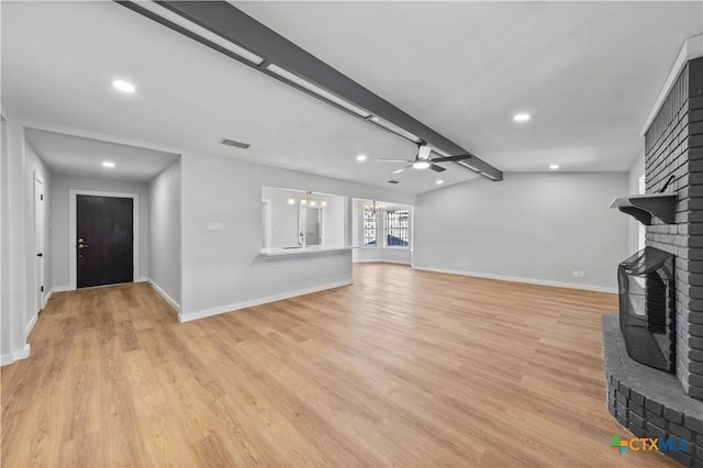 unfurnished living room featuring a fireplace, lofted ceiling with beams, ceiling fan with notable chandelier, and light wood-type flooring