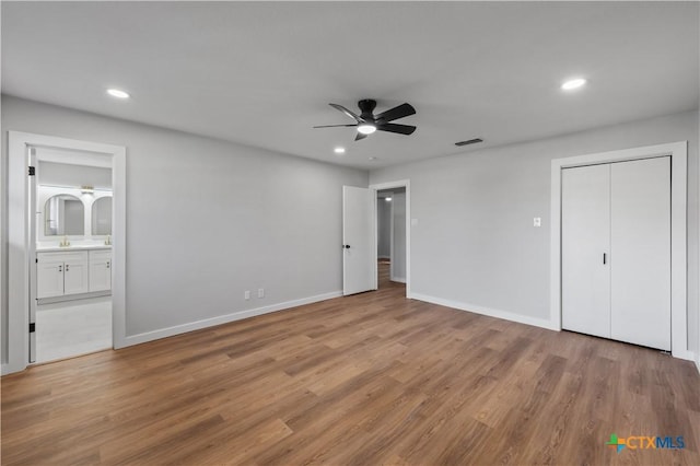 unfurnished bedroom with ceiling fan, sink, connected bathroom, and light hardwood / wood-style flooring