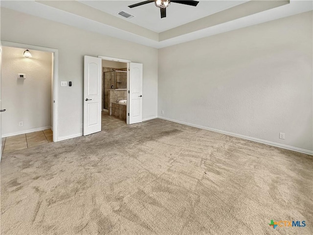 2241 Windswept Wy Way, New Braunfels, TX 78132 - unfurnished bedroom with carpet flooring, a tray ceiling, connected bathroom, ceiling fan, and tile patterned flooring