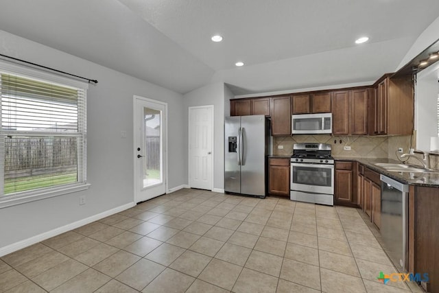 2588 Diamondback Trl, New Braunfels, TX 78130 - kitchen featuring appliances with stainless steel finishes, lofted ceiling, decorative backsplash, light tile patterned floors, and dark stone countertops