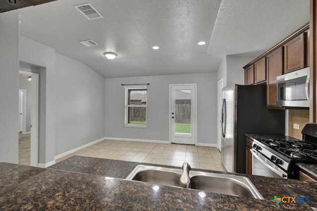 2588 Diamondback Trl, New Braunfels, TX 78130 - kitchen featuring stainless steel appliances, light tile patterned floors, backsplash, lofted ceiling, and a textured ceiling