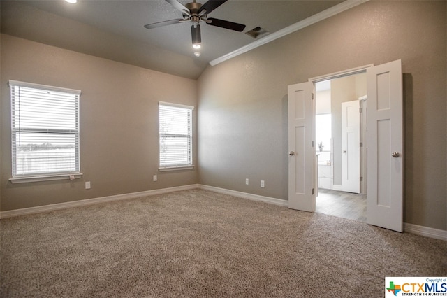 empty room with lofted ceiling, ceiling fan, carpet, and ornamental molding