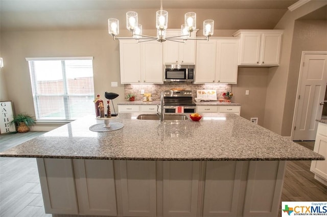 1027 Winchester Dr, Nolanville, TX 76559 - kitchen featuring appliances with stainless steel finishes, a sink, a chandelier, white cabinetry, and tasteful backsplash