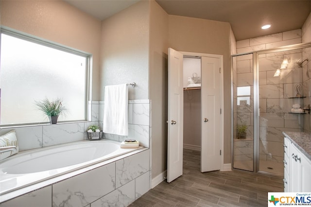 bathroom with independent shower and bath, wood-type flooring, and vanity