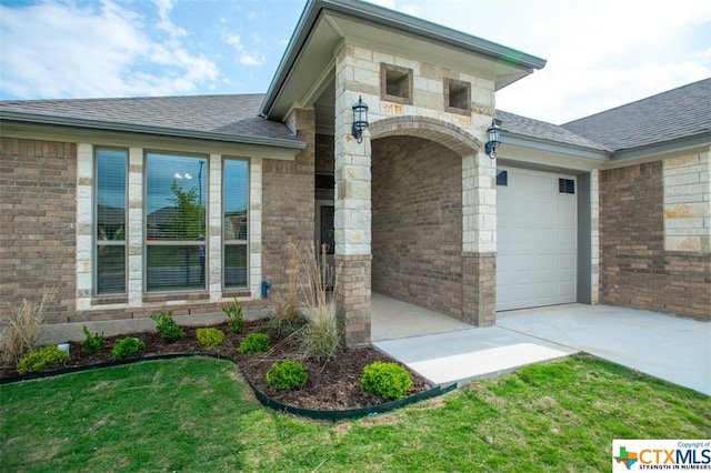 1027 Winchester Dr, Nolanville, TX 76559 - view of exterior entry with an attached garage, brick siding, roof with shingles, and a yard