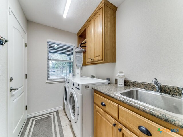 laundry area with washer and clothes dryer, sink, light tile patterned floors, and cabinets