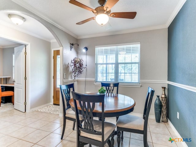 tiled dining space with ceiling fan and ornamental molding