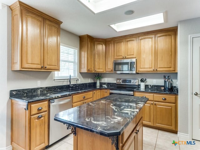 kitchen featuring light tile patterned flooring, sink, dark stone countertops, a kitchen island, and stainless steel appliances