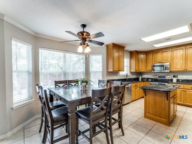 kitchen with ceiling fan, a center island, sink, stainless steel appliances, and light tile patterned flooring