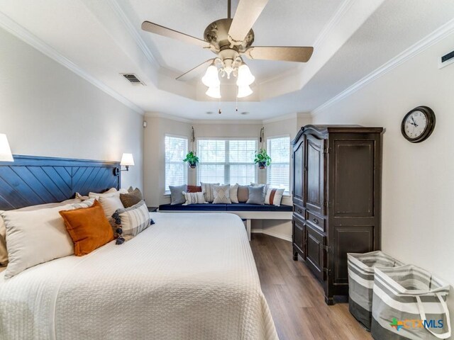 bedroom with wood-type flooring, a raised ceiling, ceiling fan, and crown molding