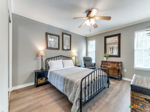 bedroom with hardwood / wood-style floors, a textured ceiling, ceiling fan, and crown molding