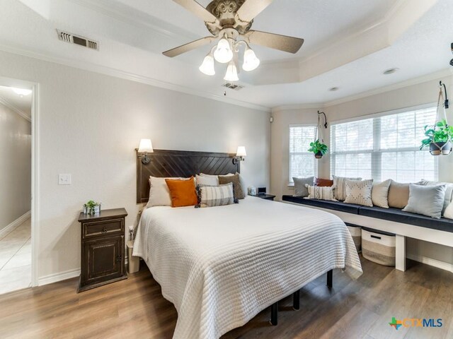 bedroom featuring a tray ceiling, ceiling fan, crown molding, and hardwood / wood-style floors