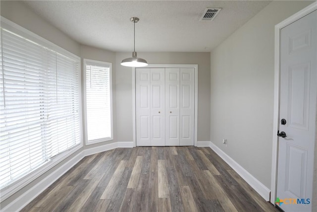 unfurnished bedroom featuring a textured ceiling, dark wood-type flooring, and a closet