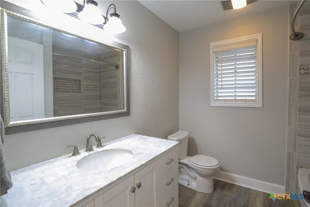 full bathroom featuring vanity, hardwood / wood-style flooring, toilet, and tiled shower / bath combo