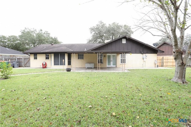 rear view of house featuring a lawn, french doors, and a patio