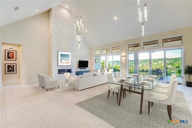 interior space with high vaulted ceiling, light tile patterned floors, a fireplace, and a wealth of natural light