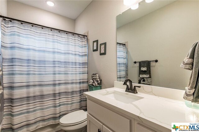 bathroom with walk in shower, vanity, and toilet