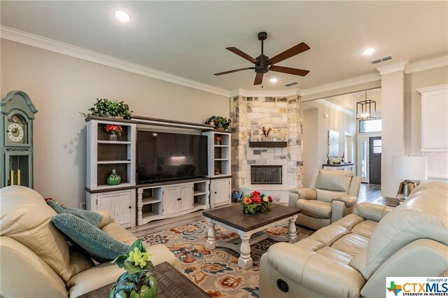 living room featuring ornamental molding, a fireplace, wood-type flooring, and ceiling fan