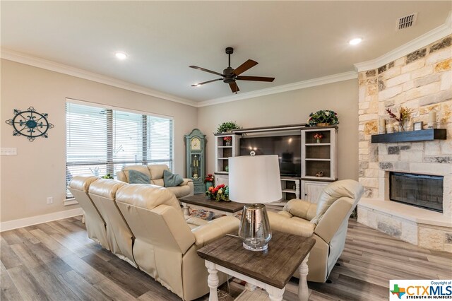 living room with ceiling fan, hardwood / wood-style floors, ornamental molding, and a fireplace