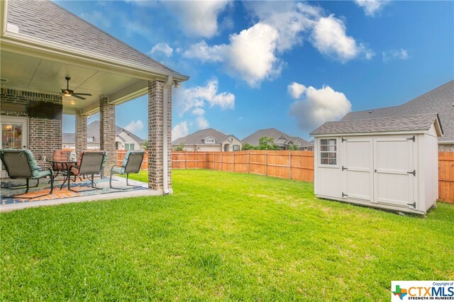 view of yard featuring a storage unit, ceiling fan, and a patio