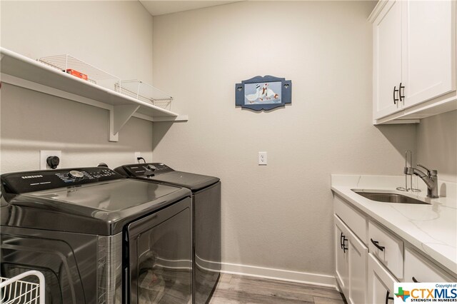 washroom featuring cabinets, wood-type flooring, sink, and washer and dryer