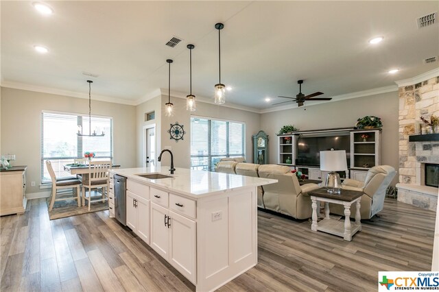 kitchen featuring white cabinetry, a center island with sink, sink, a healthy amount of sunlight, and light wood-type flooring