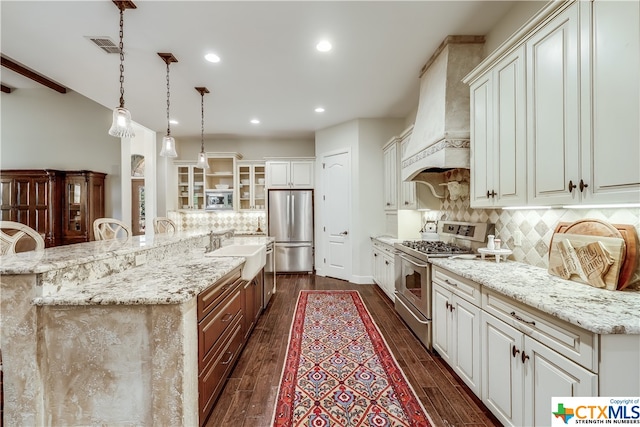 kitchen featuring dark wood-type flooring, pendant lighting, appliances with stainless steel finishes, and custom range hood