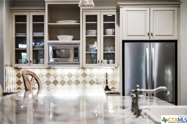 kitchen featuring sink, light stone countertops, appliances with stainless steel finishes, and decorative backsplash