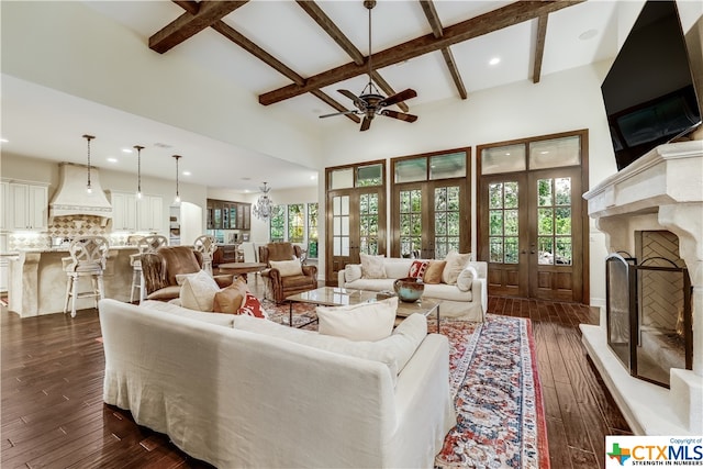 living room featuring a towering ceiling, dark wood-type flooring, beamed ceiling, and ceiling fan