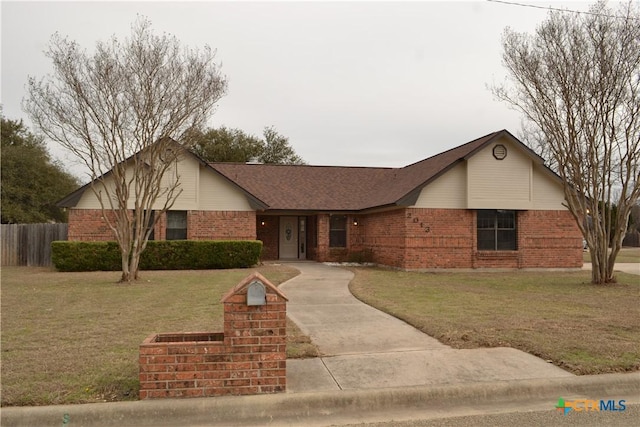 single story home featuring brick siding, fence, and a front lawn