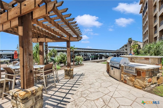 view of patio / terrace featuring a pergola, an outdoor kitchen, and a grill