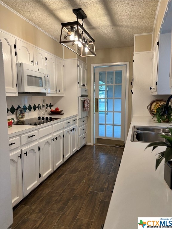 kitchen featuring sink, tasteful backsplash, oven, pendant lighting, and white cabinets