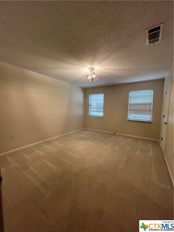 empty room with carpet and a textured ceiling