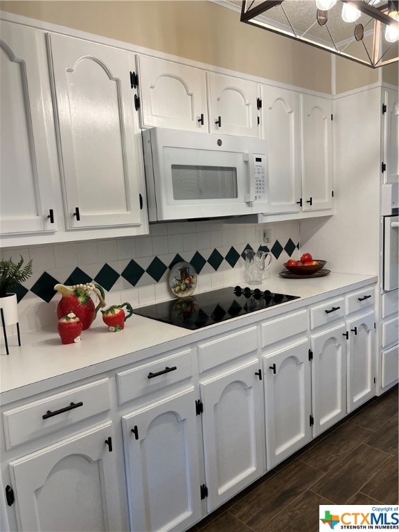 kitchen with white cabinets, oven, black electric cooktop, and tasteful backsplash