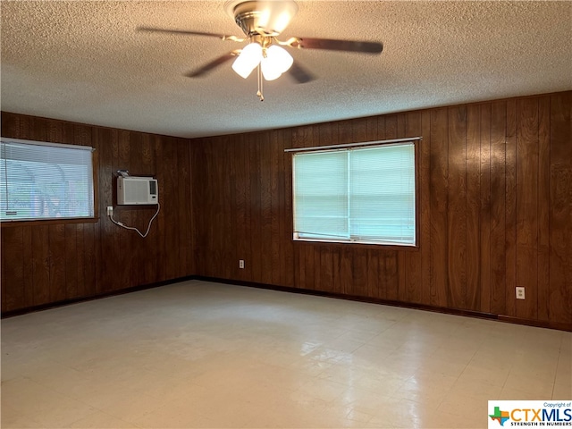 empty room featuring a textured ceiling, a wall mounted AC, ceiling fan, and wood walls